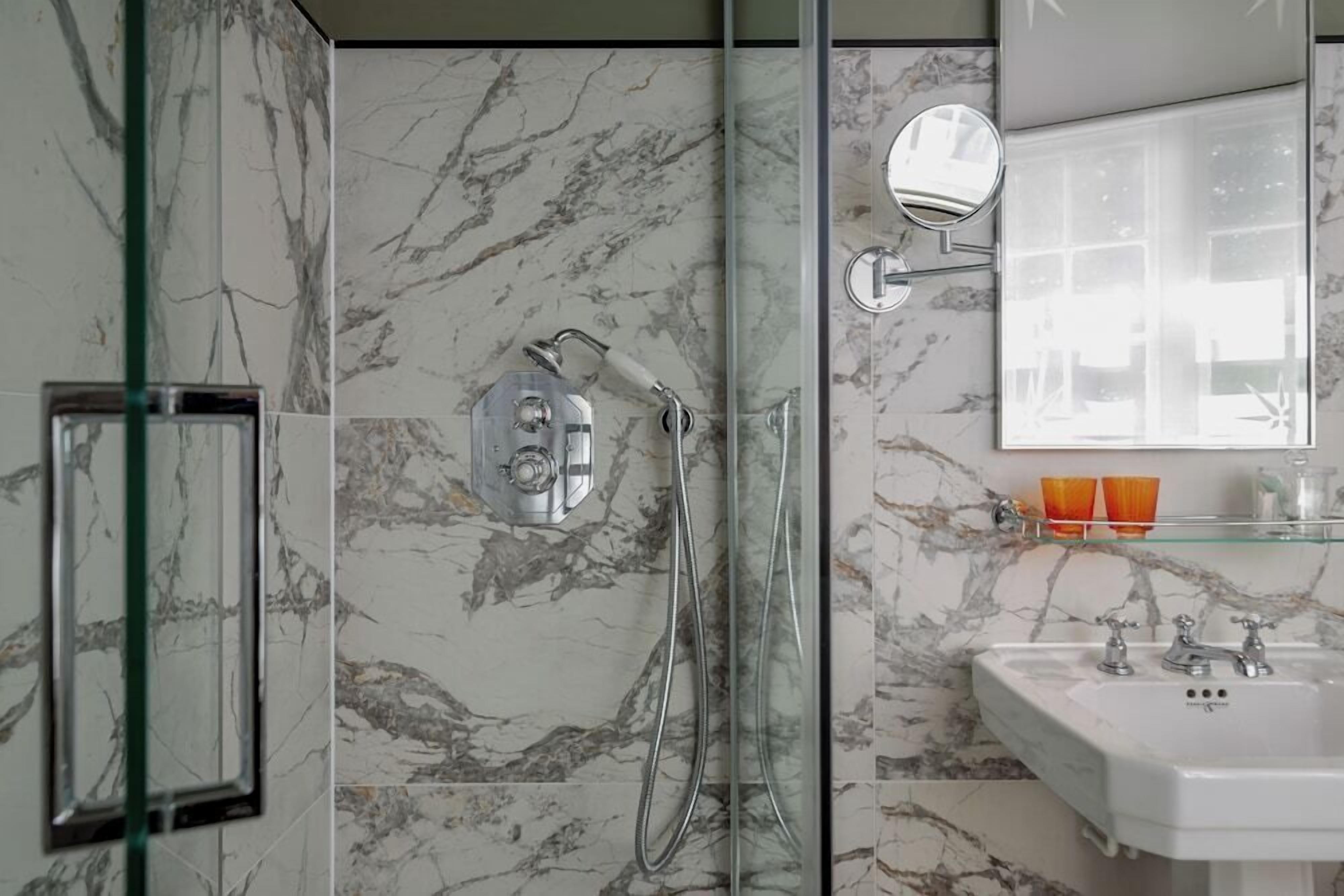 A bathroom with a glass-enclosed shower, a white sink, and a mirror.