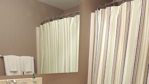 A bathroom with a sink, mirror, toilet, and striped shower curtain. - Best Location! Renovated center village Okemo 2 BR - free shuttle outside door! (Ludlow)