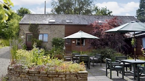 A rustic stone building with a wooden extension, outdoor seating, and a garden area. - 3 bedroom accommodation in Leintwardine, near Ludlow (Leintwardine, near Ludlow)