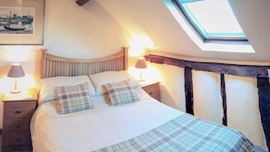 A bedroom with a bed, two bedside lamps, a nightstand, a wooden headboard, and a skylight. - 3 bedroom accommodation in Leintwardine, near Ludlow (Leintwardine, near Ludlow)