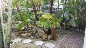 A garden with palm trees, a hammock, and stepping stones.