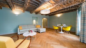 A room with a herringbone wooden floor, a striped sofa, a round white table, and yellow chairs. - Old Royal Post Apartments (Prague)