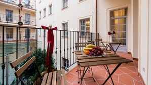 A balcony with a table set with fruit, a bench, and a railing with a red bow. - Old Royal Post Apartments (Prague)