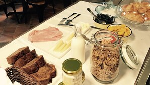 A breakfast buffet with various food items, a tufted headboard, and a coat rack. - Old Royal Post Apartments (Prague)