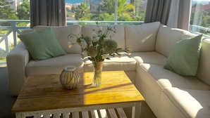 Ein weißes Sofa mit grünen Kissen, ein Holztisch und eine Vase mit Blumen.