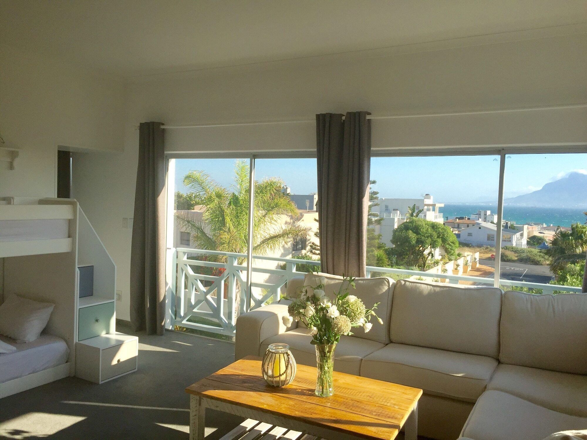 A modern living room with a sofa, a wooden coffee table, and a view of a coastal cityscape.