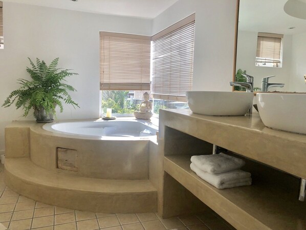 A modern bathroom with a freestanding bathtub, a large mirror, and a potted plant. - 5 Options - Guest House (Cape Town)