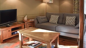 Un salon avec un canapé, une table basse, un téléviseur et deux lampes.