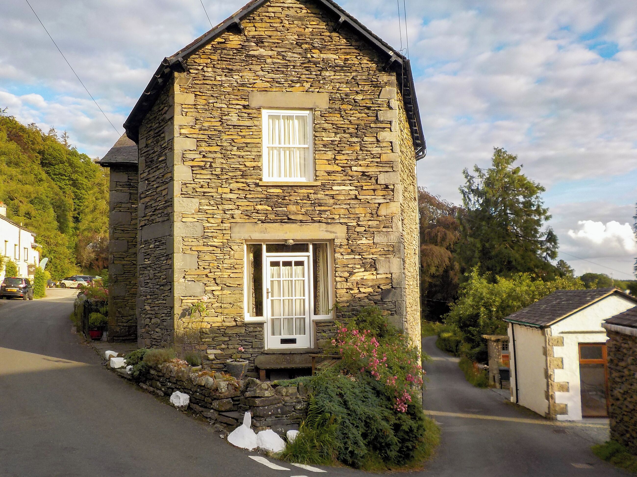 A stone house with two windows, a small porch, and a garden.