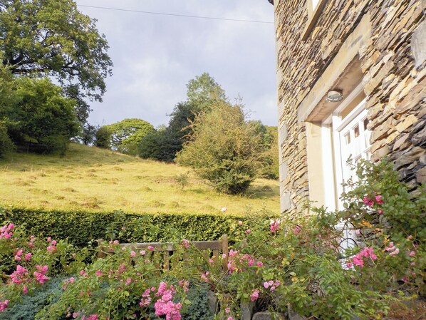 A stone building with a wooden fence and pink flowers in the foreground.