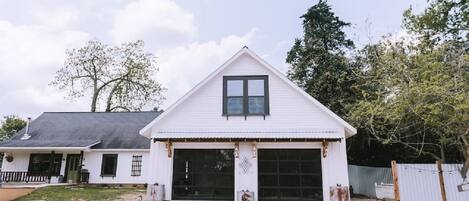 Une maison de plain-pied avec un garage, un porche à l’avant et une cour clôturée.
