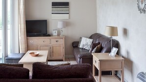 A living room with a sofa, a coffee table, a TV, and a lamp. - Pine Rigg - Quarry Rigg (Bowness-on-Windermere)