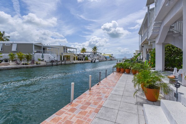 A waterfront property with a canal, potted plants, and a dock.