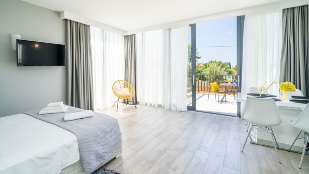 A modern hotel room with a bed, a desk, and a balcony with outdoor seating. - Apartments Zoom Zoom-Studio Apartment with Balcony (Grey) (Dubrovnik)
