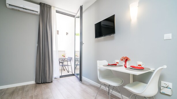 A modern dining area with a table, chairs, and a flat-screen TV mounted on the wall.