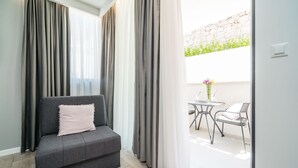 Una sala de estar moderna con un sofá gris, una mesita con un jarrón y un balcón con mobiliario exterior.