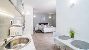 Una habitación de hotel moderna con una cama grande, un escritorio pequeño, un lavamanos y una planta en maceta.