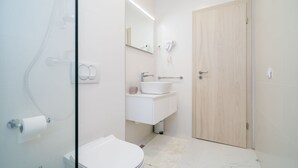 Un baño moderno con inodoro, lavamanos y ducha.