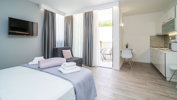 Una habitación de hotel moderna con cama, televisión, escritorio y kitchenette.