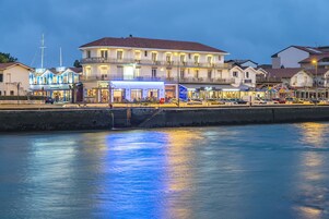A waterfront hotel with multiple stories, a balcony, and a view of the water.