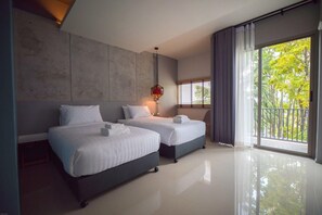 Una moderna camera d'hotel con due letti, un'ampia finestra vista su spazi verdi e un lampadario.