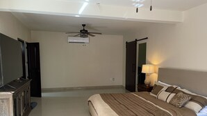 A bedroom with a bed, a ceiling fan, an air conditioning unit, a TV, and a nightstand with a lamp. - Pool and close to ocean (Túxpam de Rodríguez Cano)