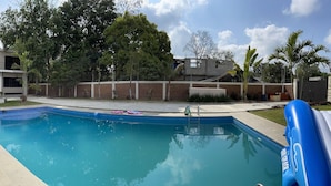 A modern outdoor swimming pool with a stone pathway leading to it, surrounded by a well-maintained lawn and a variety of plants. - Pool and close to ocean (Túxpam de Rodríguez Cano)