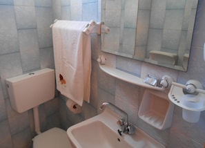 A bathroom with a toilet, sink, and mirror. - Oasis Studios (Kefalonia)