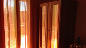 A room with a cabinet and a table with a bottle and glasses. - Oasis Studios (Kefalonia)