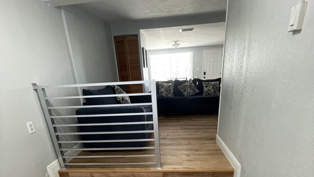 A staircase with a metal railing leading to a living area with a couch and a door.