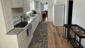 A kitchen with white cabinets, a granite countertop, a stainless steel sink, and a black trash bin.