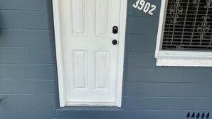 A white door with a black handle, a mailbox, and a house number 3902 on a grey wall.