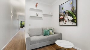 A modern living room with a grey sofa, a small round table, and a large wildlife painting on the wall.