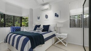 A bedroom with a bed, bedside tables, and a window with a view of greenery.