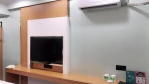 A room with a wooden TV stand, a flat-screen TV, and a small table with two mugs. - Greentree Inn Chongqing Longhushidai Tianjie Xietaizi Subway Station H (Chongqing)
