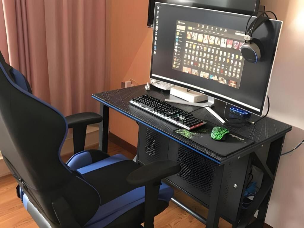 A gaming chair, a desk with a computer, and a monitor.