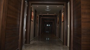 A long, narrow hallway with wooden paneling on the walls and a polished floor. - Hide Away Suites (Noida)
