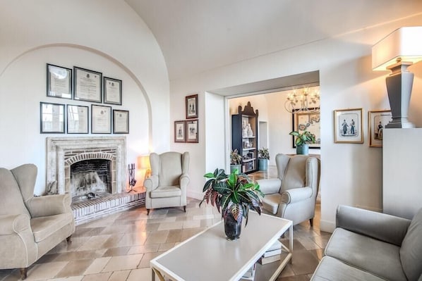 Una sala de estar con chimenea, certificados enmarcados y una planta grande.