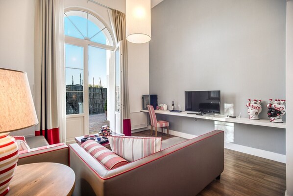 A modern living room with a sofa, a TV, and a dining area. - Palazzo del Barone (Massa Lubrense)