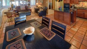 A spacious living room with a dark wooden dining table, leather sofas, and a chandelier. - Hale Lani ~ Big Island Charmer with Panoramic Ocean Views ~ Near Best Beaches (Kamuela)