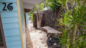 A pathway leading to a house with a stone wall and tropical plants. - Hale Lani ~ Big Island Charmer with Panoramic Ocean Views ~ Near Best Beaches (Kamuela)