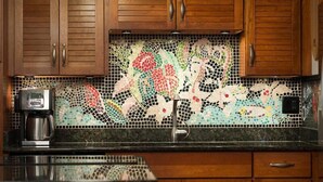 A kitchen with wooden cabinets, a coffee maker, and a mosaic backsplash. - Hale Lani ~ Big Island Charmer with Panoramic Ocean Views ~ Near Best Beaches (Kamuela)