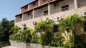 Edificio a più piani con facciata in pietra, condizionatori d'aria e un balcone con ringhiere.