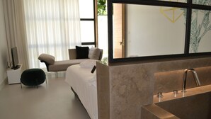 Ein modernes Hotelzimmer mit einer großen Badewanne, einer Couch und einem Fernseher.