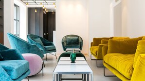 Ein modernes Wohnzimmer mit Türkis- und Gelbs Sofas, einem Glastisch und Pendelleuchten.