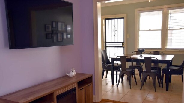 A living room with a fireplace, a TV mounted on the wall, and a dining area with chairs and a table. - Your Home away from Home in Memphis, Tn. Minutes from all Memphis attractions (Memphis)