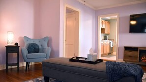 A living room with a grey sofa, a blue armchair, and a small side table. There is a TV mounted on the wall and a fireplace. - Your Home away from Home in Memphis, Tn. Minutes from all Memphis attractions (Memphis)