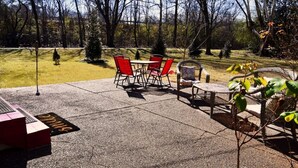 An outdoor patio with a concrete floor, red chairs, wicker furniture, and a small tree. - Your Home away from Home in Memphis, Tn. Minutes from all Memphis attractions (Memphis)