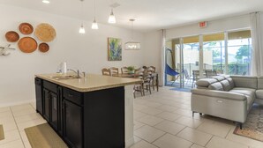 Een moderne keuken met een centraal eiland, een eethoek met stoelen en een bank.