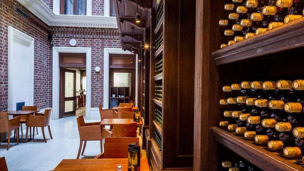 A restaurant with brick walls, wooden tables, and a wine rack filled with bottles. - Palazzo Rosso (Poznań)